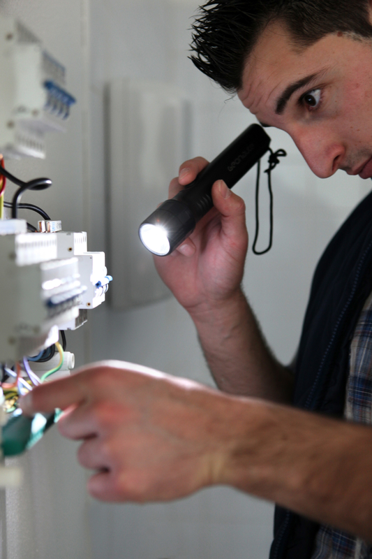 Electrician shining a torch on a fusebox